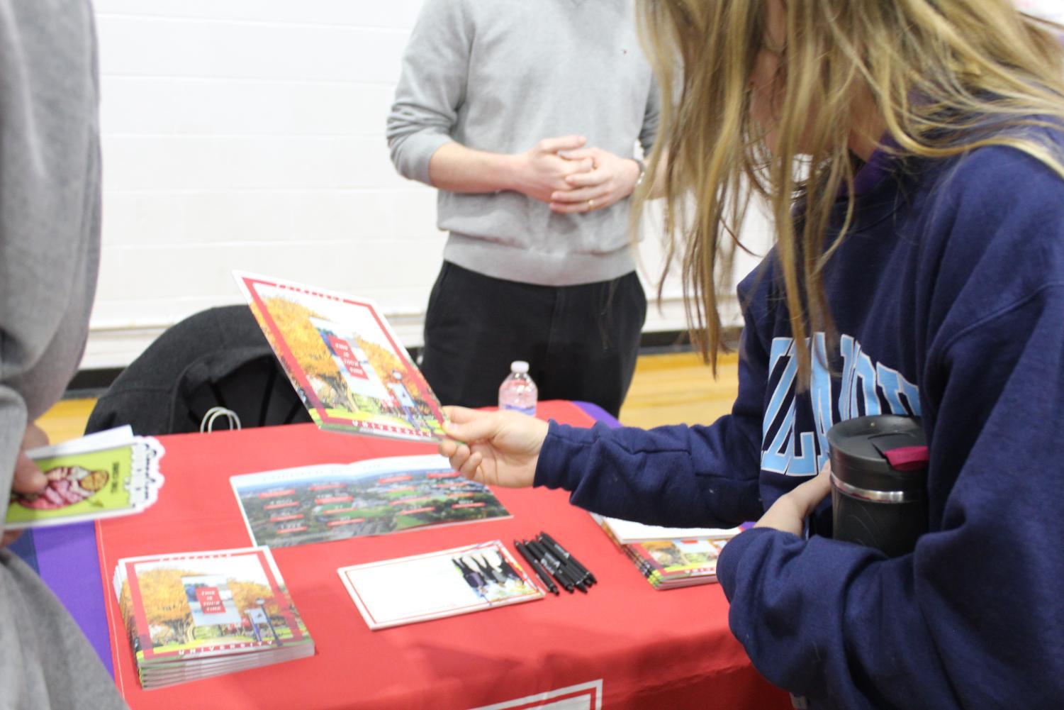 Senior Emma Gomes sifts through school pamphlets at the college fair.