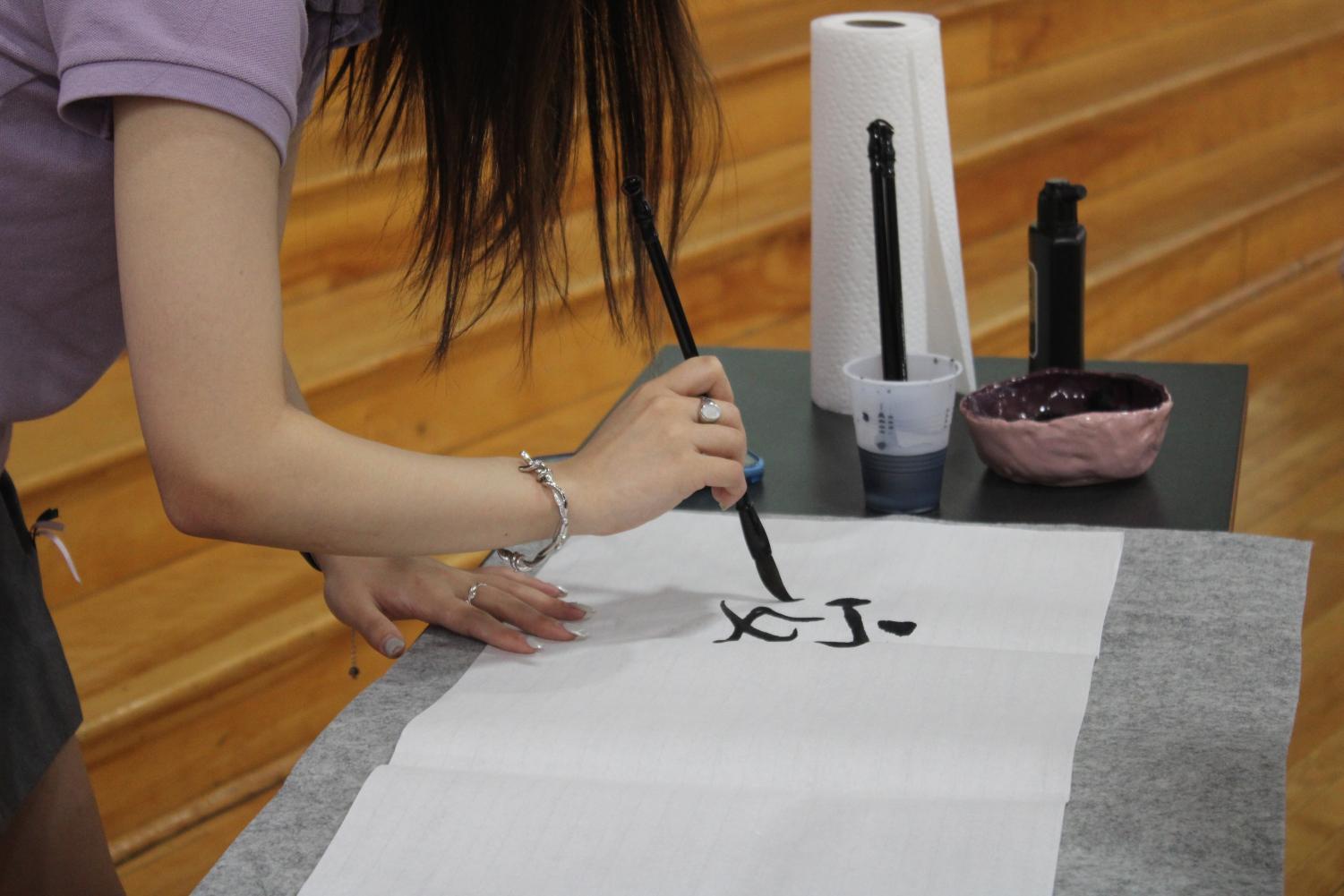 Student Catherine Yifan Jin writing calligraphy.