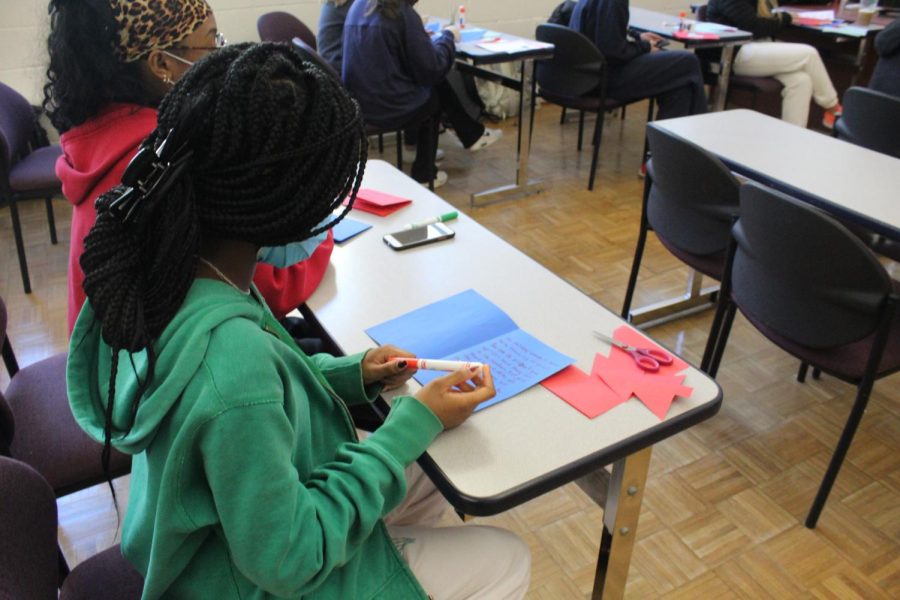 Students in a classroom writing cards for Holy Cross Gives Thanks