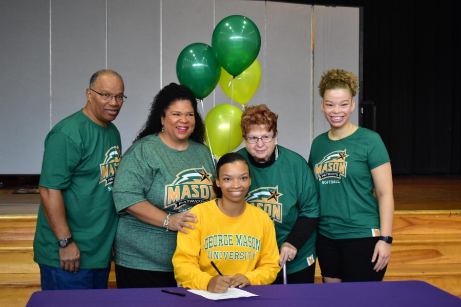 Cheyenne+DeGross%2C+accompanied+by+her+family%2C+recreating+the+signing+of+her+D1+acceptance+to+George+Mason+University.+