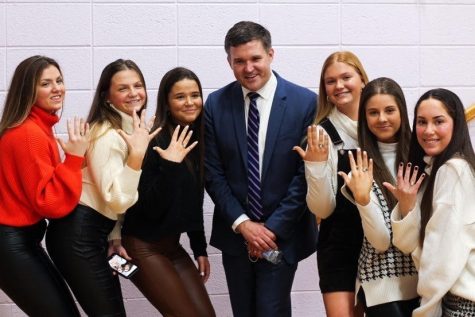 three junior girls on each side of Mr.Sullivan holding up their hands to show their junior rings off.