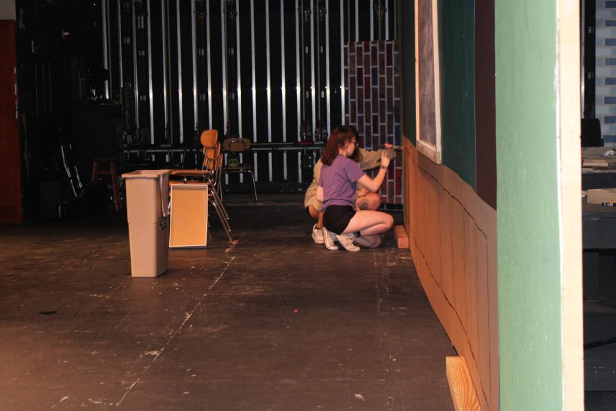 Seniors Emma Allan and Maddie Beins paint sets for the upcoming School of Rock production.