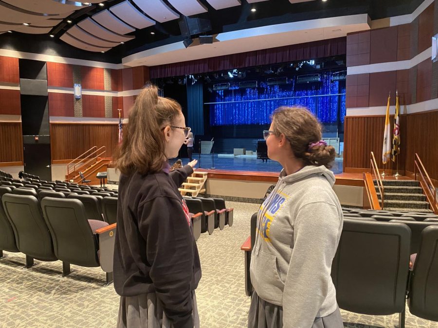 Two students standing by a stage talking