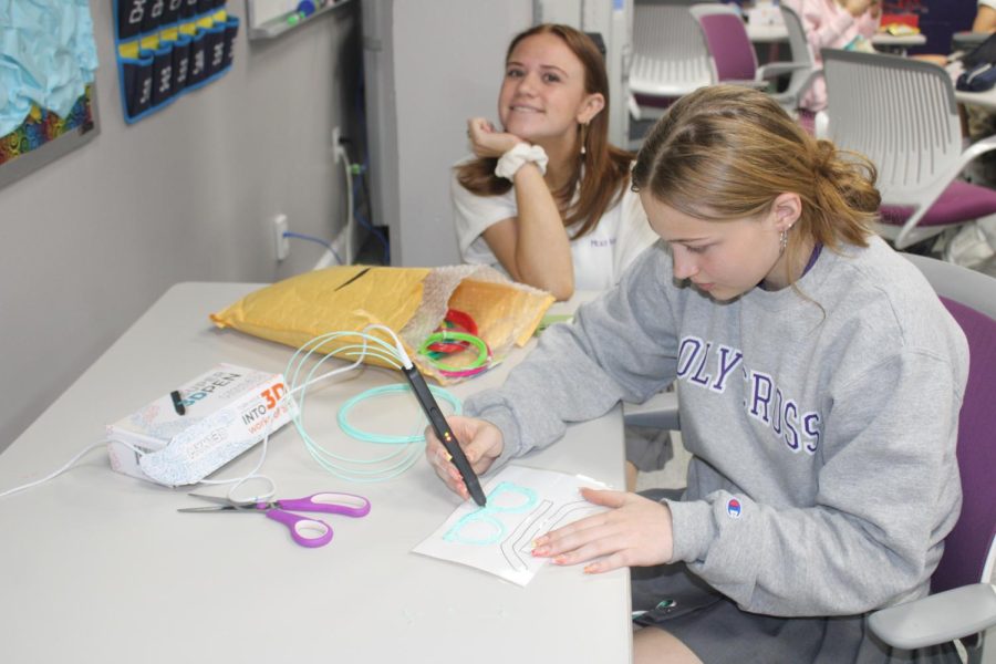 Sophomore Emma Ryan works on her Tech class PBA, making 3d print glasses. While, junior Jillian Puglisi admires. 