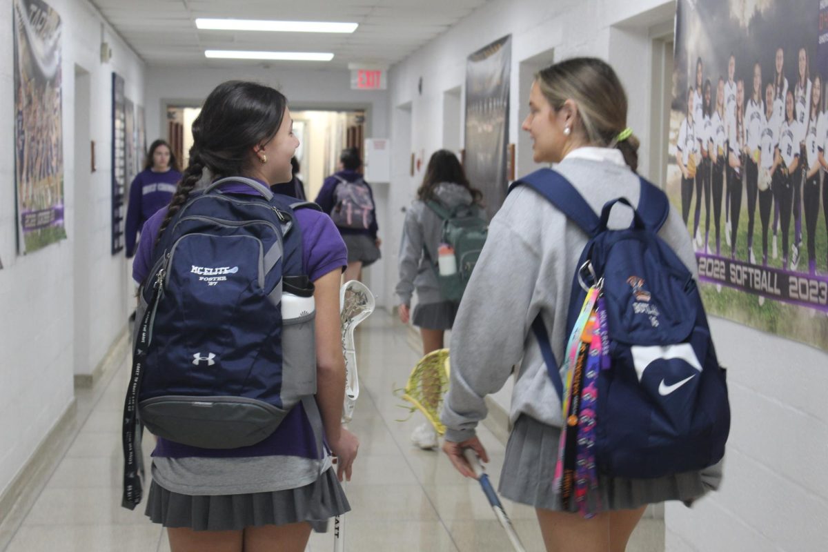 Freshman student-athletes Sabrina Foster and Reilly Boylan walk toward the locker room before classes start at 8:00 am to put away the lacrosse gear that they will need for tryouts at the end of the day. 