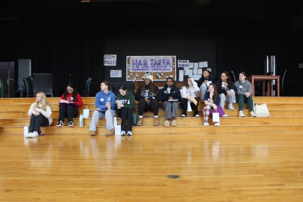 A group of teenagers sits on the stage.